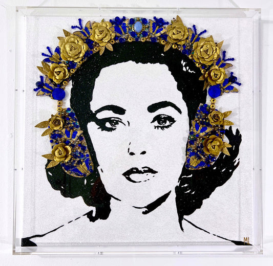 Black and white portrait of Elizabeth Taylor with an elaborate gold and blue floral crown embellishing her hair, set against a white background.
