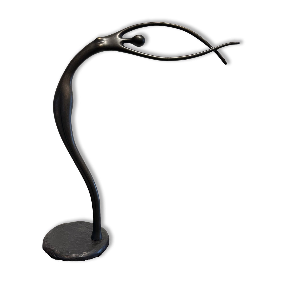 A sleek, abstract black sculpture resembling a slender, elongated figure with outstretched arms balanced on a round base.