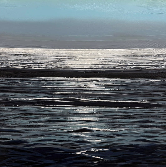 Sunlight reflects off gentle waves on a calm ocean under a blue sky, with the horizon visible in the distance.