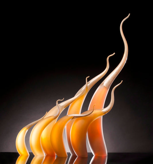 Six curved, orange and yellow glass sculptures on a black background.