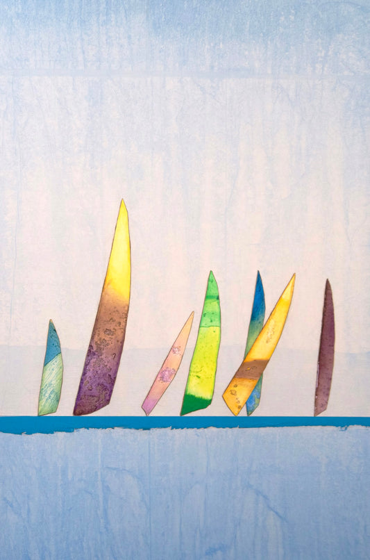 Colorful, abstract sailboat shapes are arranged upright on a blue surface with a light blue background, evoking a minimalist seascape.