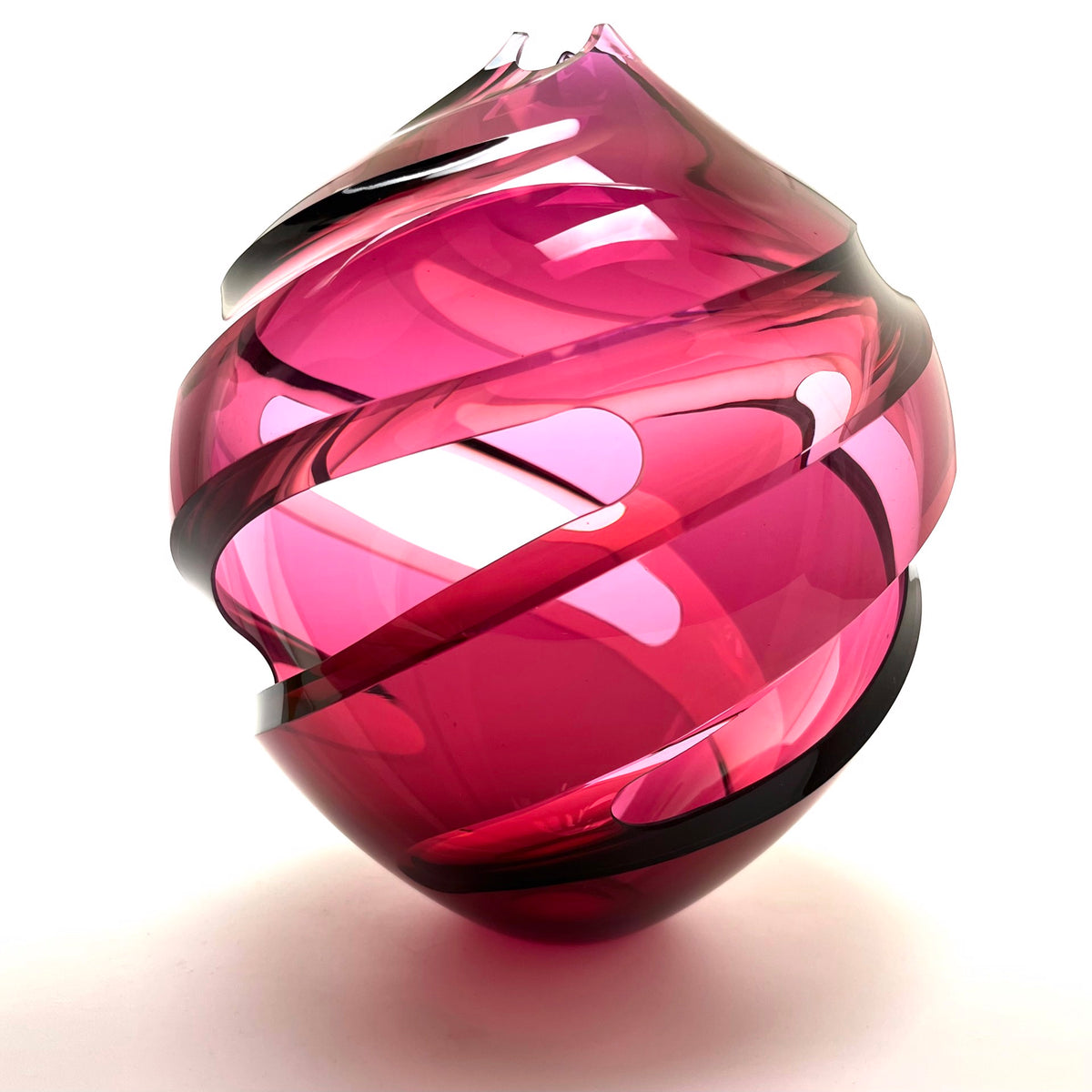 Pink glass sculpture with a spiral of cutouts on a white background.