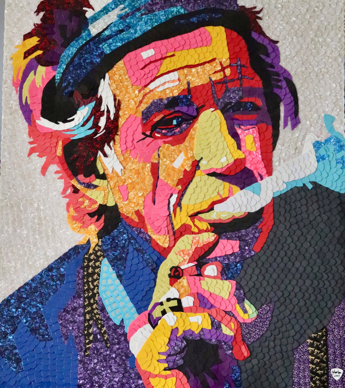 Colorful mosaic-style portrait of an older man in a hat holding a cigarette.