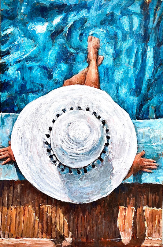 Person with a wide hat sits poolside, feet in blue water, viewed from above.