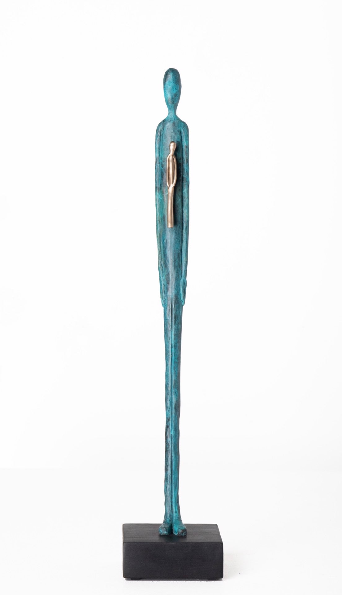 Tall, slender teal sculpture of a standing human figure with a smaller silver figure embedded in its chest, displayed on a black rectangular base.