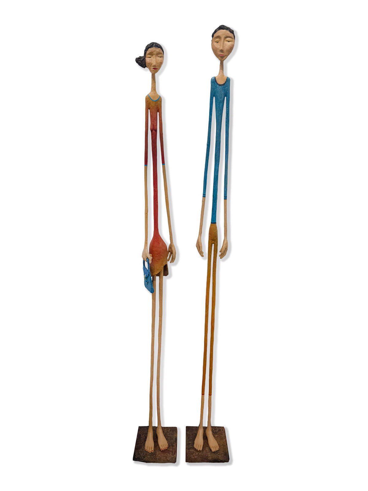 Two tall, slender wooden figure sculptures with elongated limbs on rectangular bases.