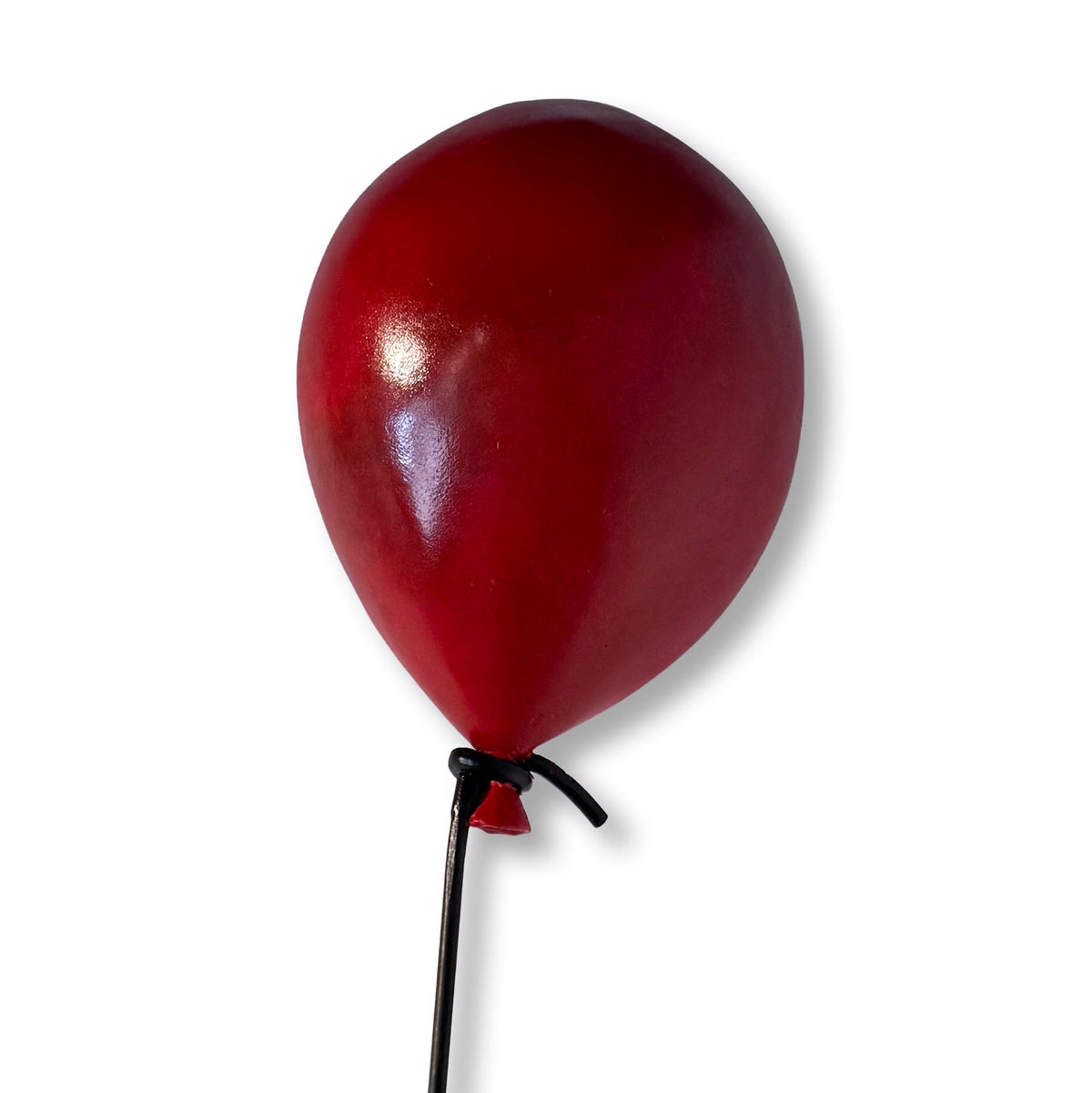 Minimalist sculpture of a stick figure floating while holding a red balloon. (view 3)