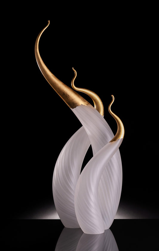 Three white glass sculptures with gold tips, rising in elegant, curved forms.