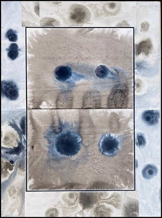 Abstract painting with blue and gray ink blotches and stains on a textured background, featuring darker circular shapes in the center and lighter spots along the edges.