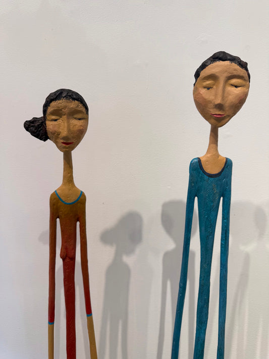 Two tall, slender wooden figure sculptures with elongated limbs on rectangular bases. (view 2)