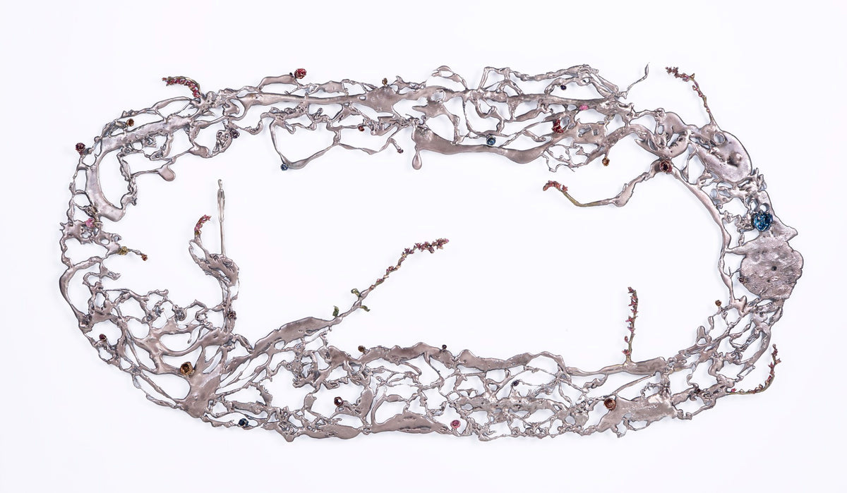 Large, irregular metallic wall structure with winding branches and embedded small colored elements, arranged in an oval shape.