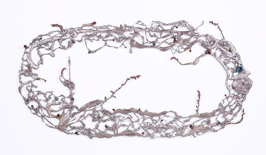 Large, irregular metallic wall structure with winding branches and embedded small colored elements, arranged in an oval shape.