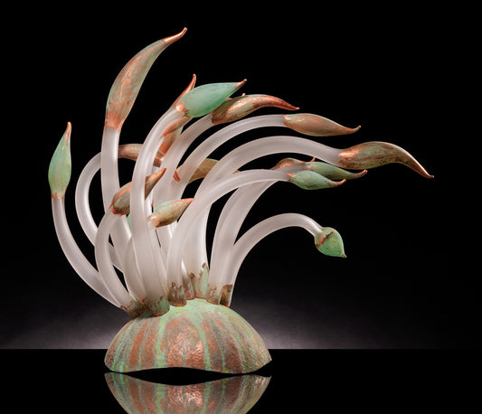 Curved glass sculpture resembling plant shoots with green and copper tips.
