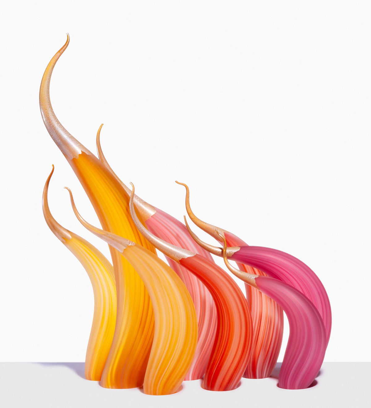 Curved glass sculptures in orange, yellow, and pink on a white surface.