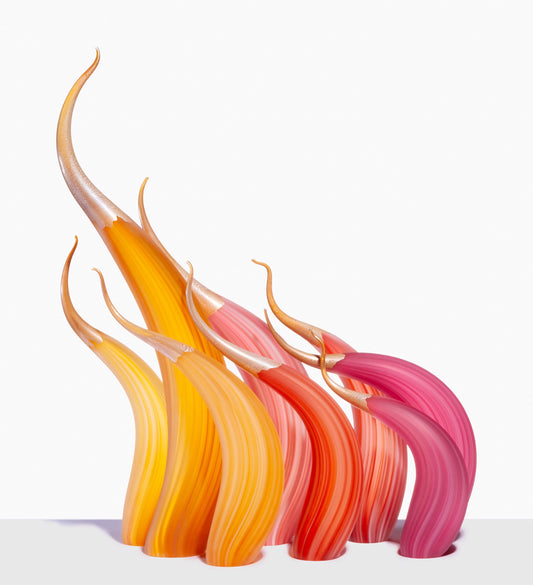 Curved glass sculptures in orange, yellow, and pink on a white surface.
