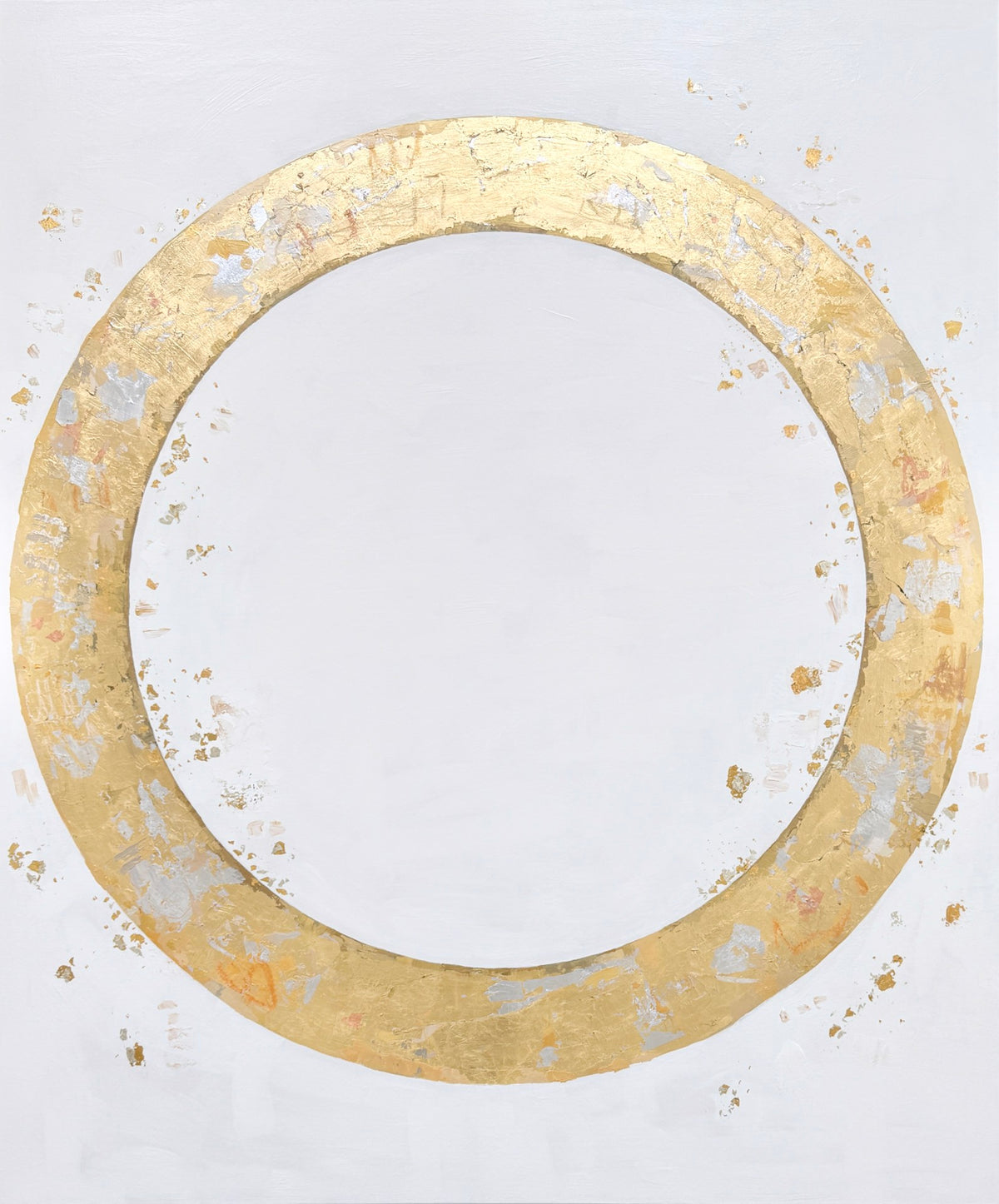 A large gold circular ring with a textured surface on a white background. Small gold and silver flakes surround the ring.