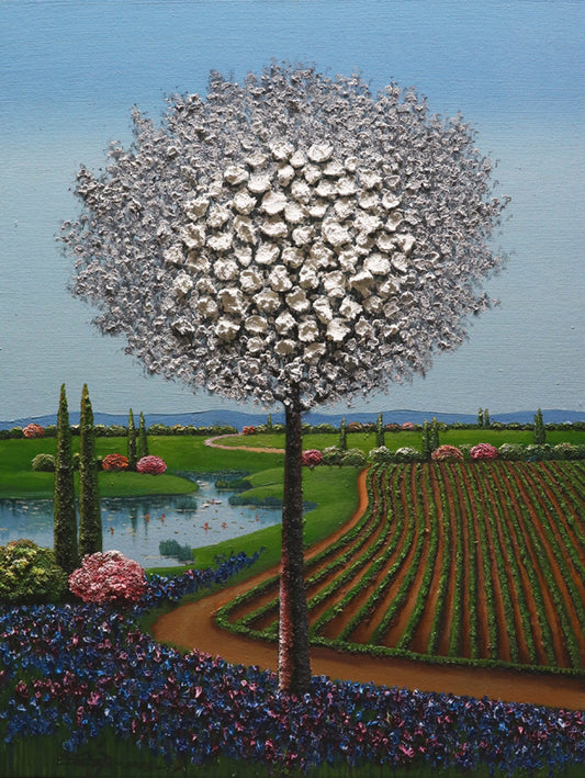 A tree with a large, spherical, white blossom stands by a lake amid fields and gardens under a clear blue sky.