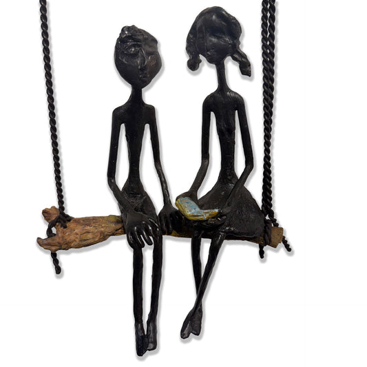 Metal sculpture of two figures on a bench lifted by three blue balloons. (view 2)