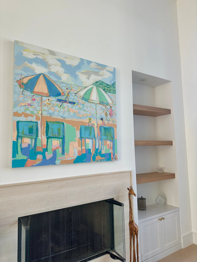 Emyo painting of colorful beach umbrellas and chairs above a fireplace with built-in shelves in a South Florida living room