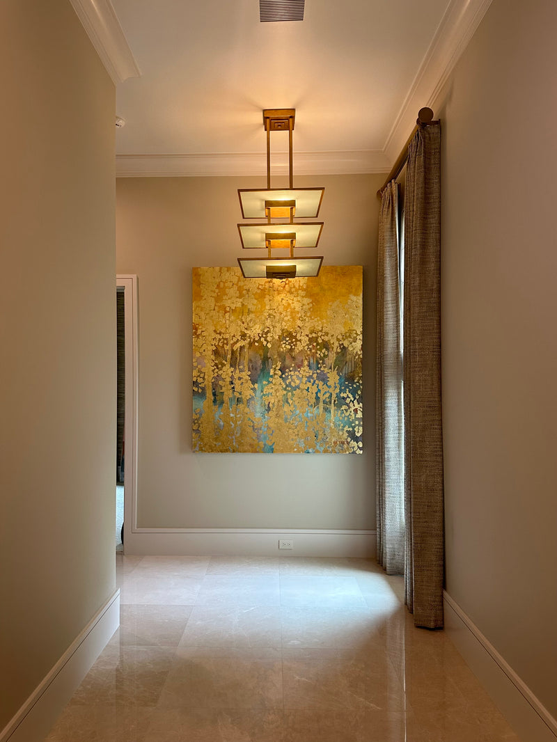 Nancy Reyner gold and teal forest painting at the end of a marble-floored hallway under a modern pendant light