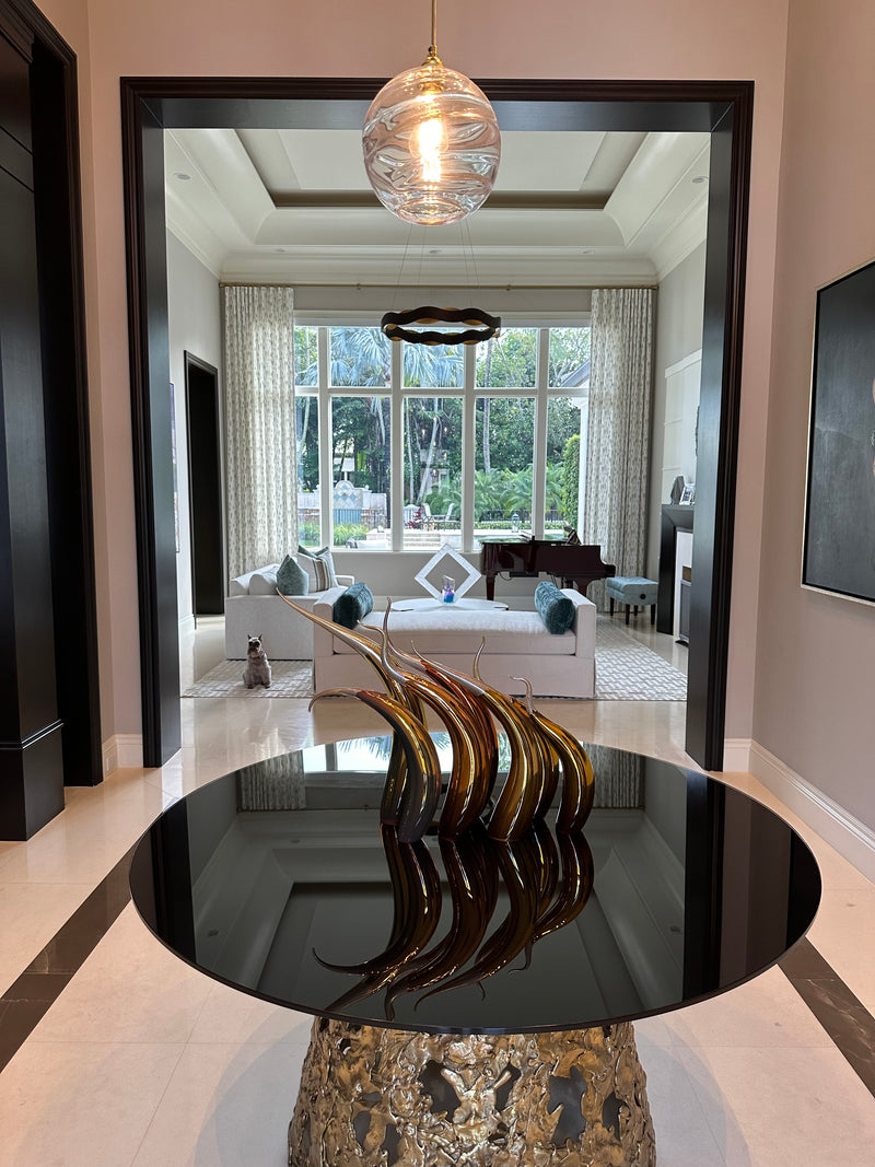 Rick Eggert bronze flame sculpture on a round black glass entry table, looking into a formal living room