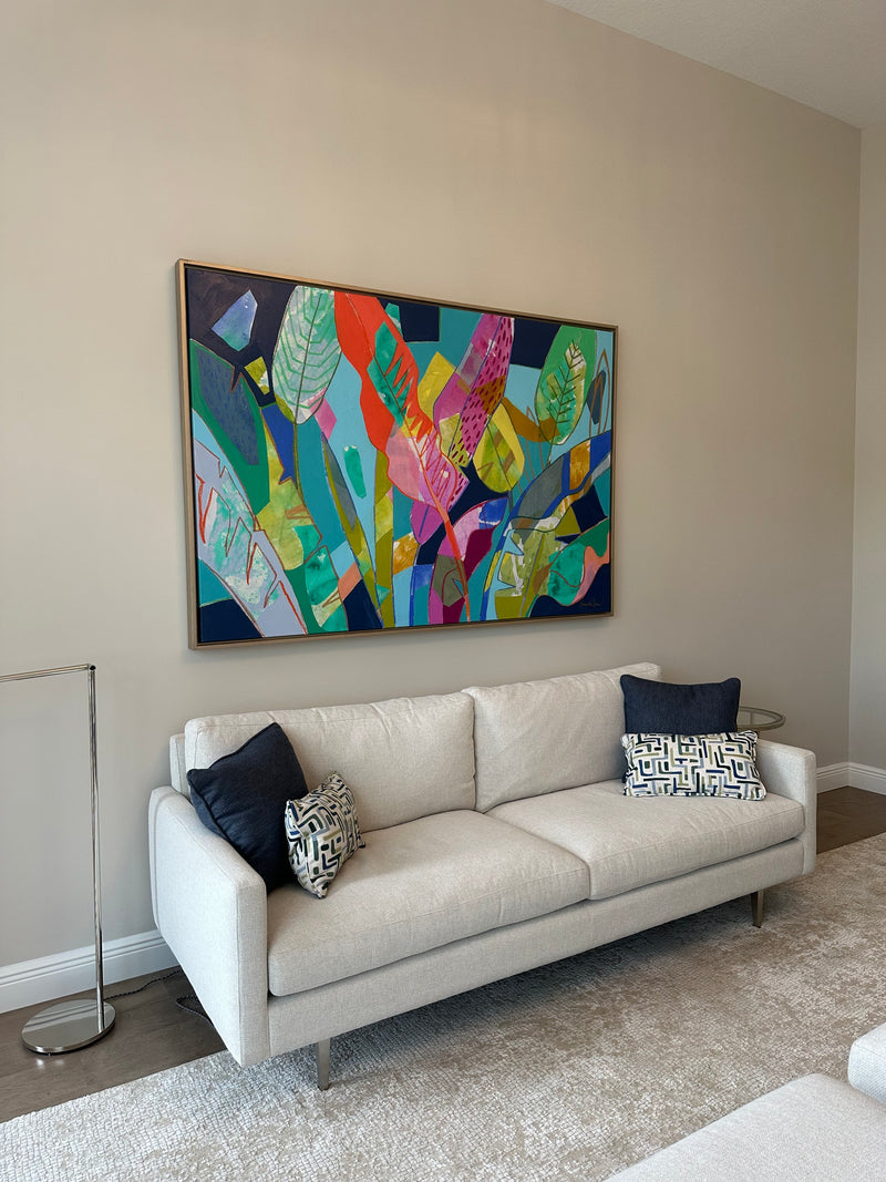 Hannah Lane vibrant abstract of layered tropical leaves in pink, teal and green above a white sofa
