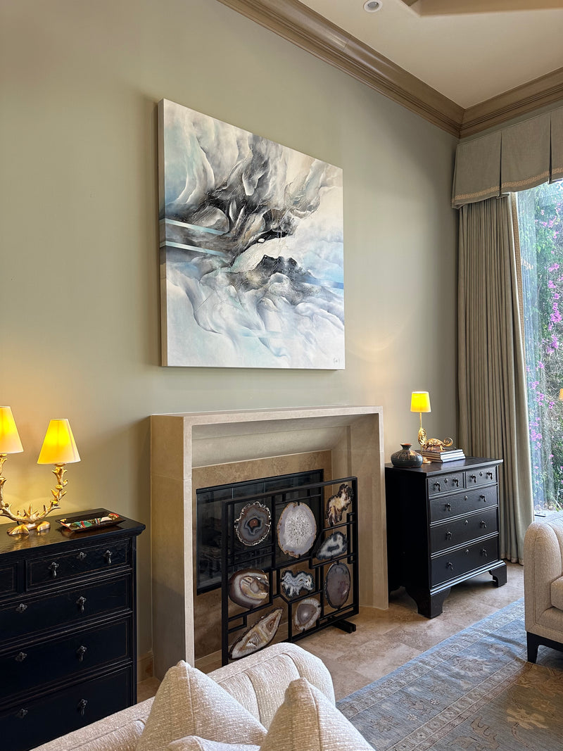 Nina K black, white and blue abstract painting above a stone fireplace in a traditional living room