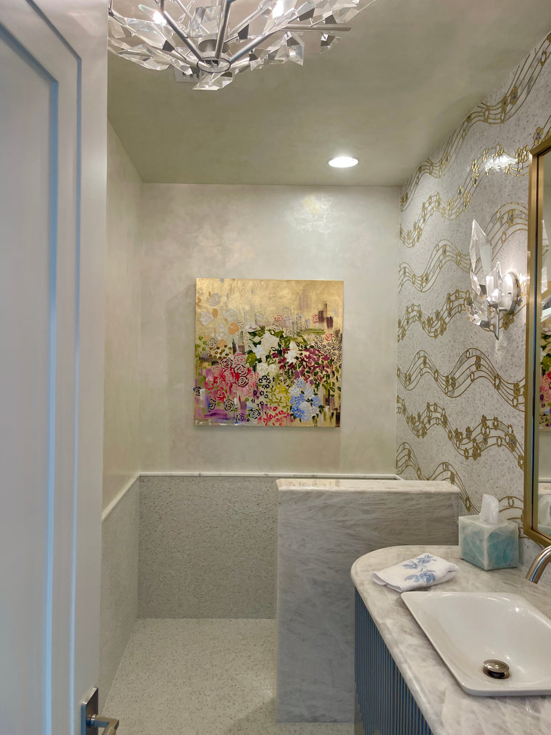 Michelle Sakhai's colorful floral painting with gold accents in an elegant powder room with music-note wallpaper