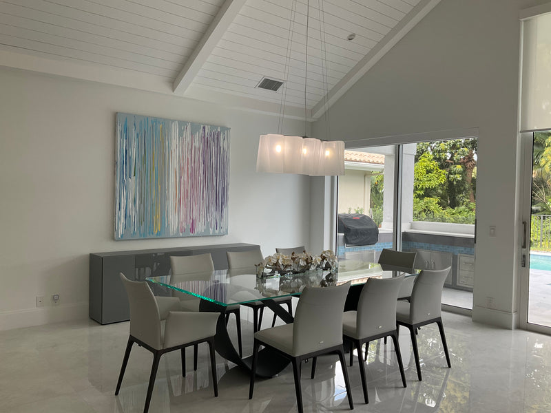 John Schuyler abstract with vertical drips of blue, lavender and yellow in a dining room overlooking a pool