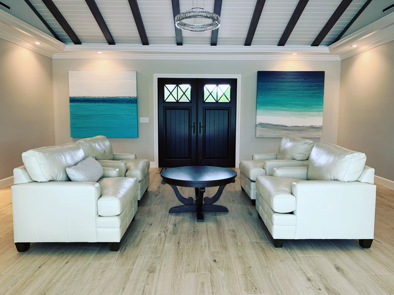 Pair of Stephanie Paige turquoise seascape artworks flanking double front doors in a coastal great room