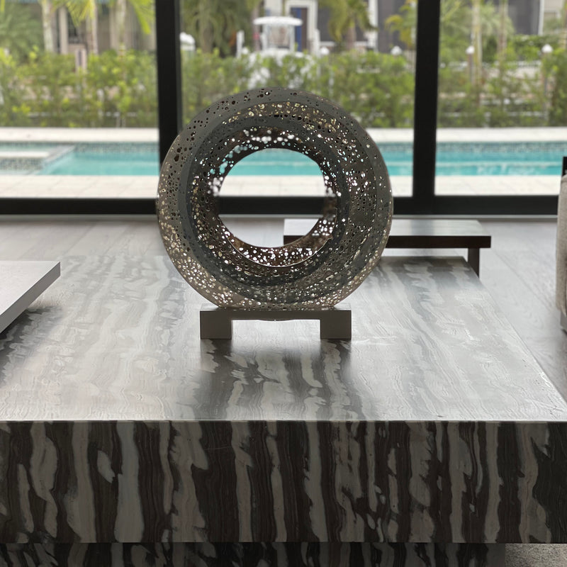 Karen Bexfield pierced circular sculpture on a marble coffee table with a pool view in a South Florida home