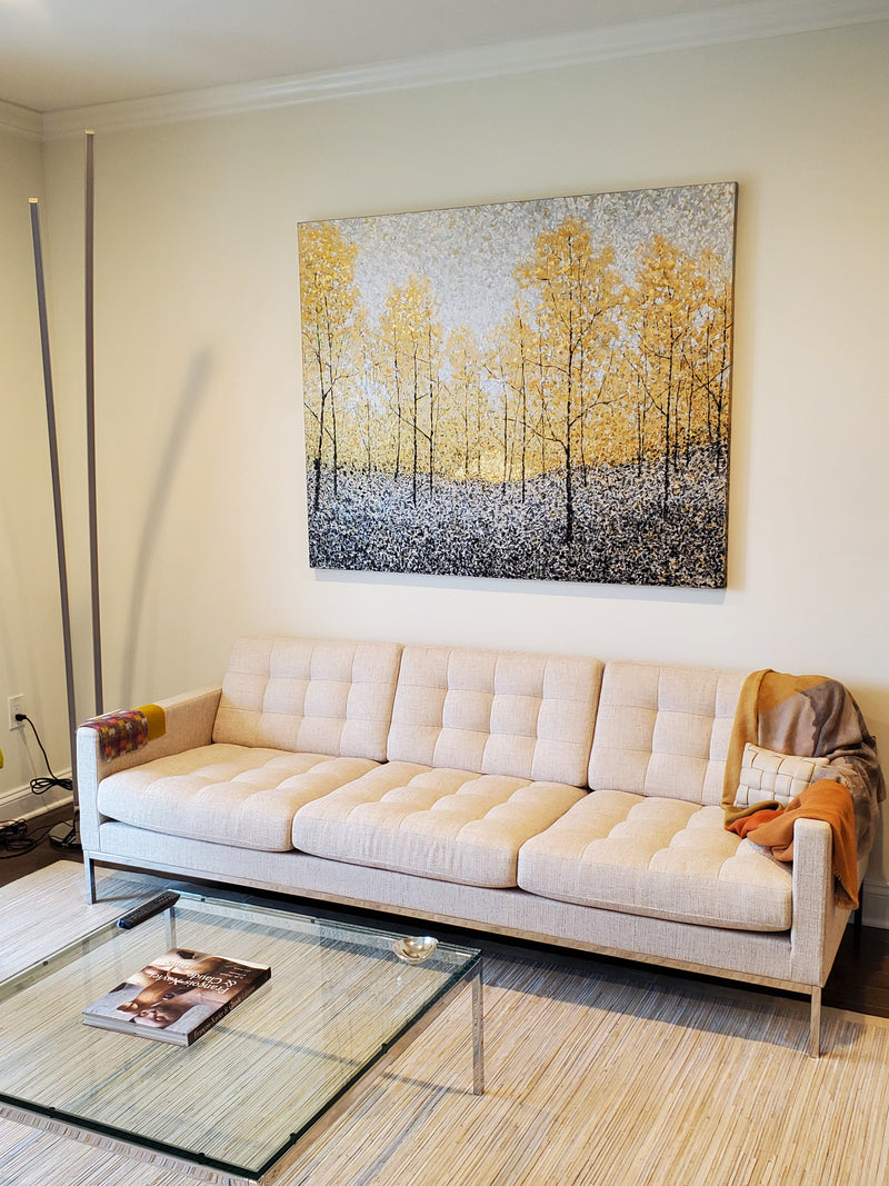 Barrett Edwards painting of golden birch trees above a tufted cream sofa in a living room