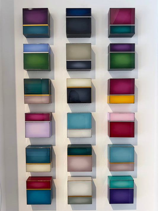 Sixteen colorful, translucent wall-mounted boxes arranged in a grid pattern.