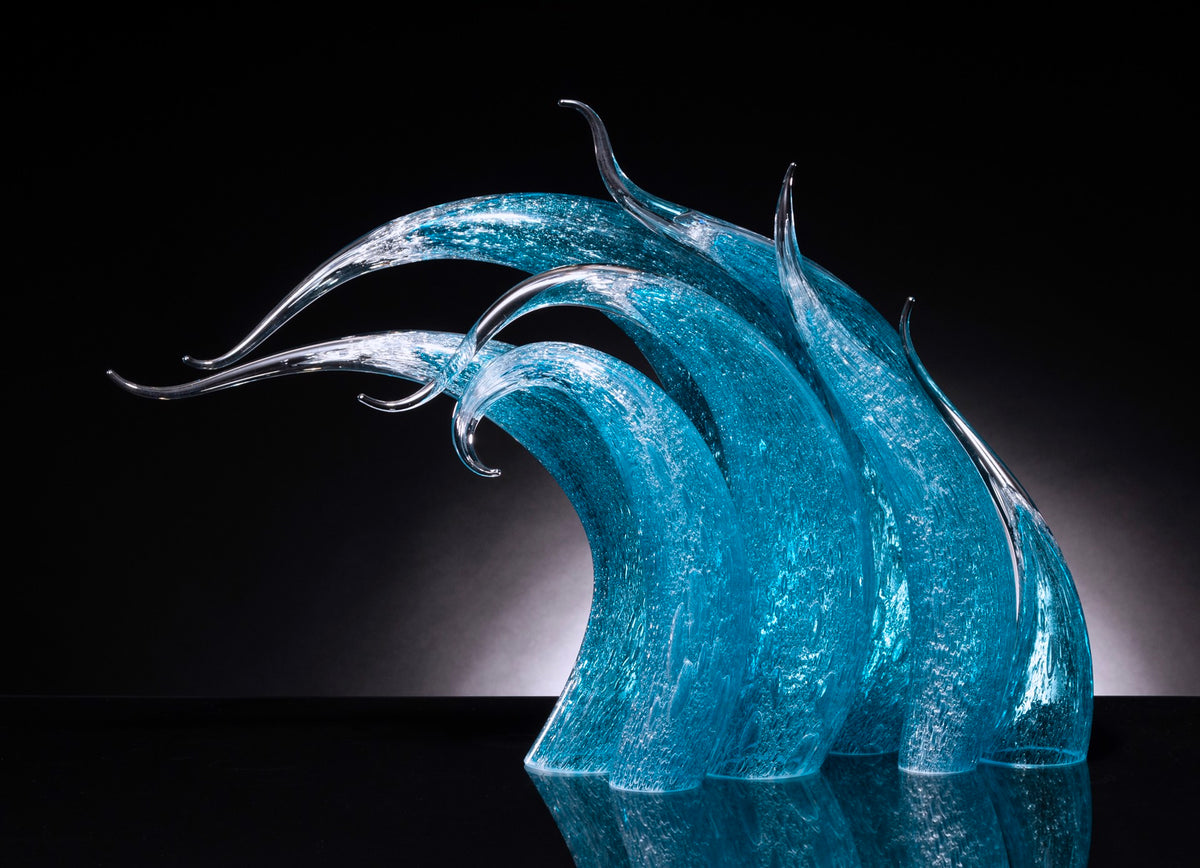 Seven curved, semi-transparent blue glass sculptures with elongated tips stand against a black background.