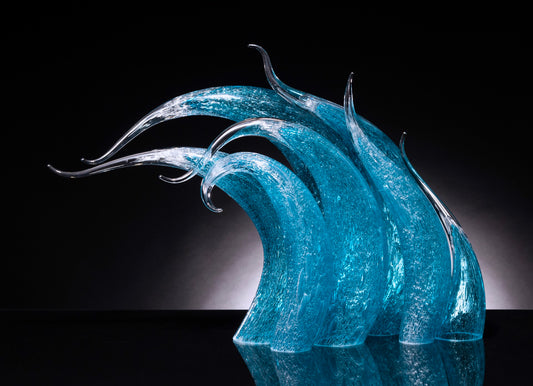 Seven curved, semi-transparent blue glass sculptures with elongated tips stand against a black background.
