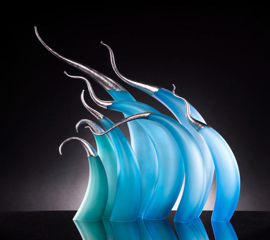 Curved blue and teal glass sculptures with silver tips on a black background.