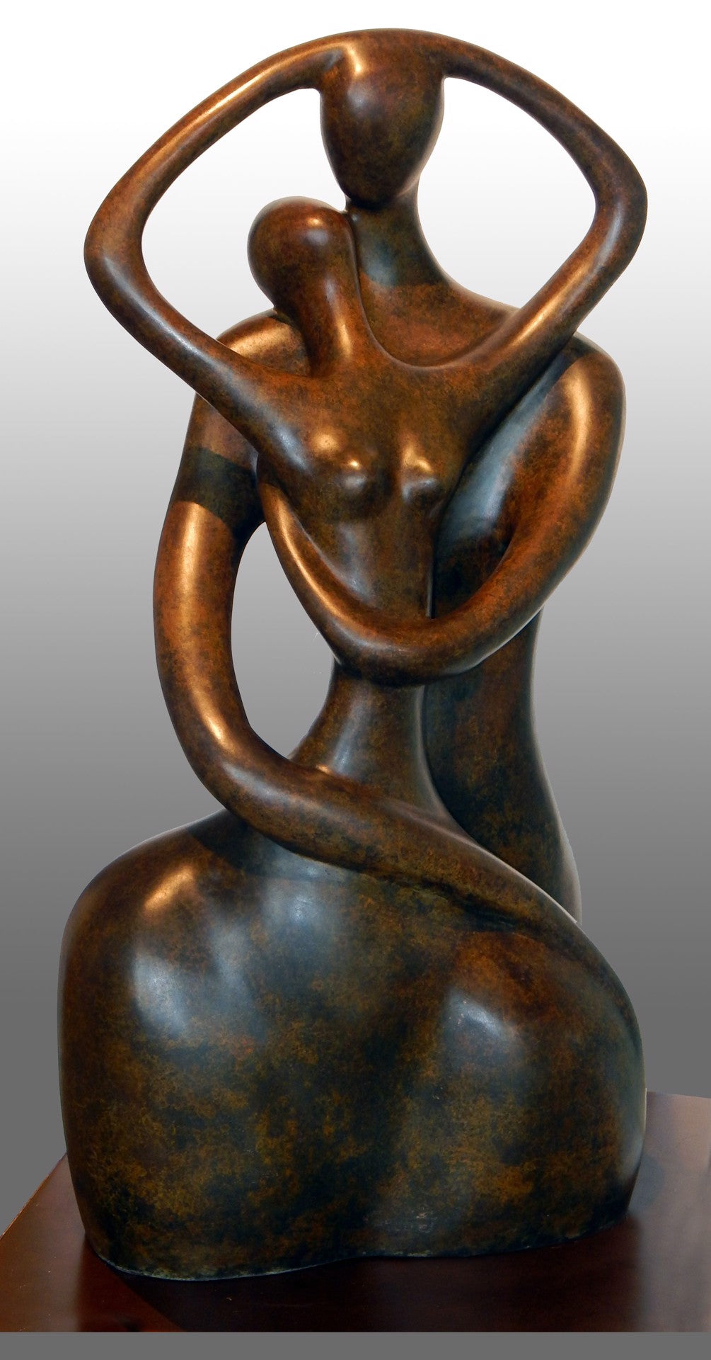 Bronze sculpture of two abstract figures embracing, featuring elongated arms and simplified forms.
